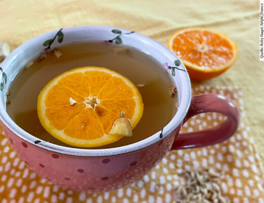 Eine Tasse Tee mit Orangenscheibe darin.