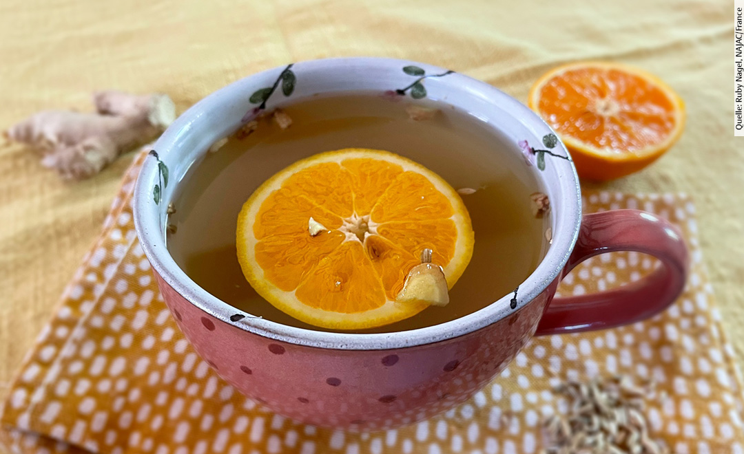 Eine Tasse Tee mit Orangenscheibe darin.