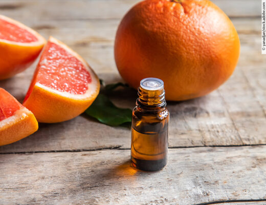 Fläschchen mit ätherischem Öl vor einem Hintergrund von Zitrusfrüchten/Orangen/Grapefruits.